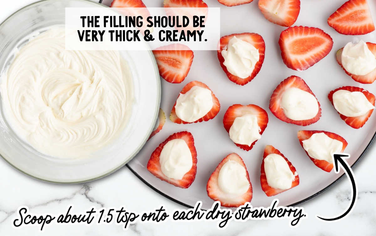 Thick cheesecake filling being spooned onto sliced strawberries for deviled strawberries