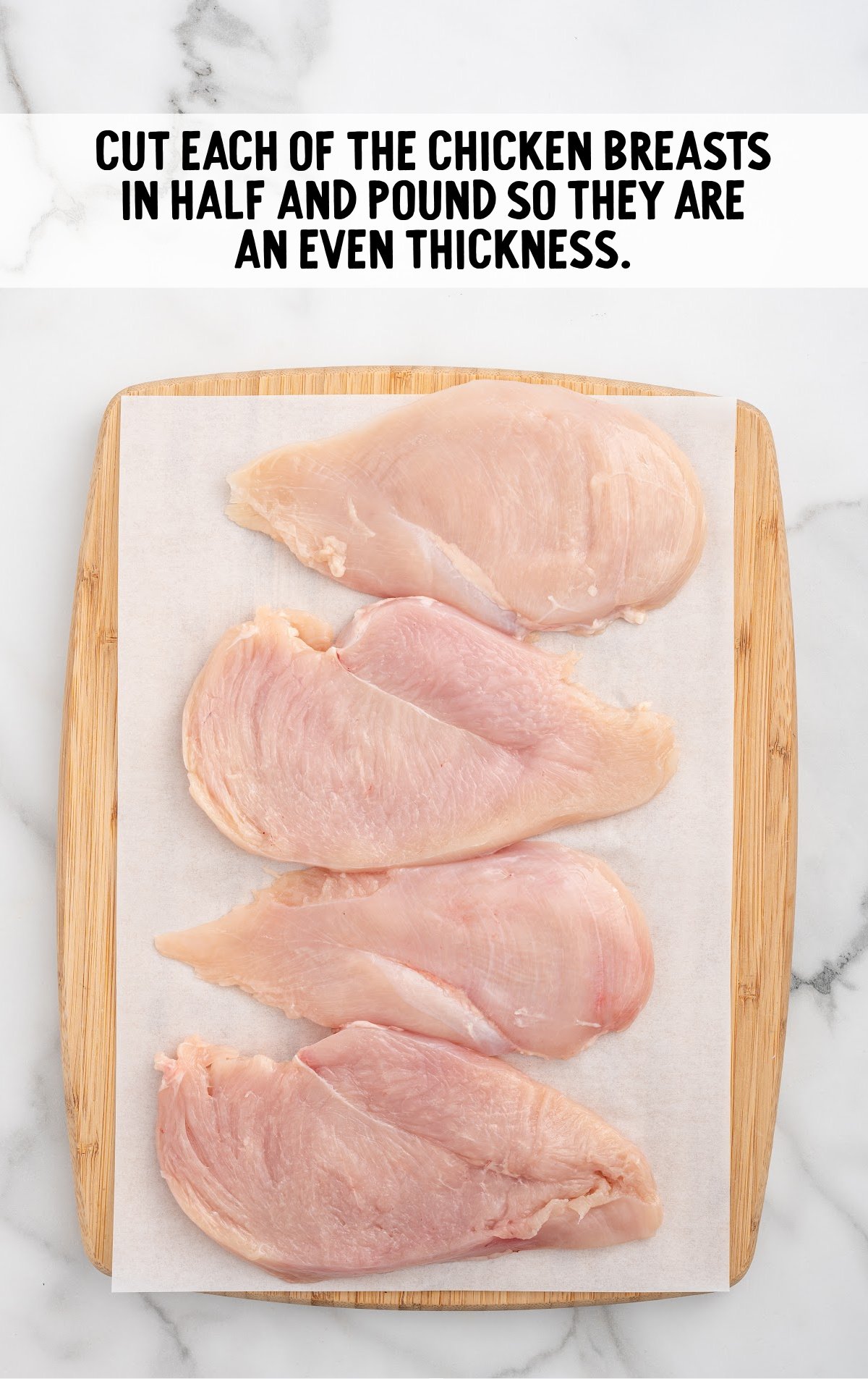 chicken breast cut into half on a wooden board