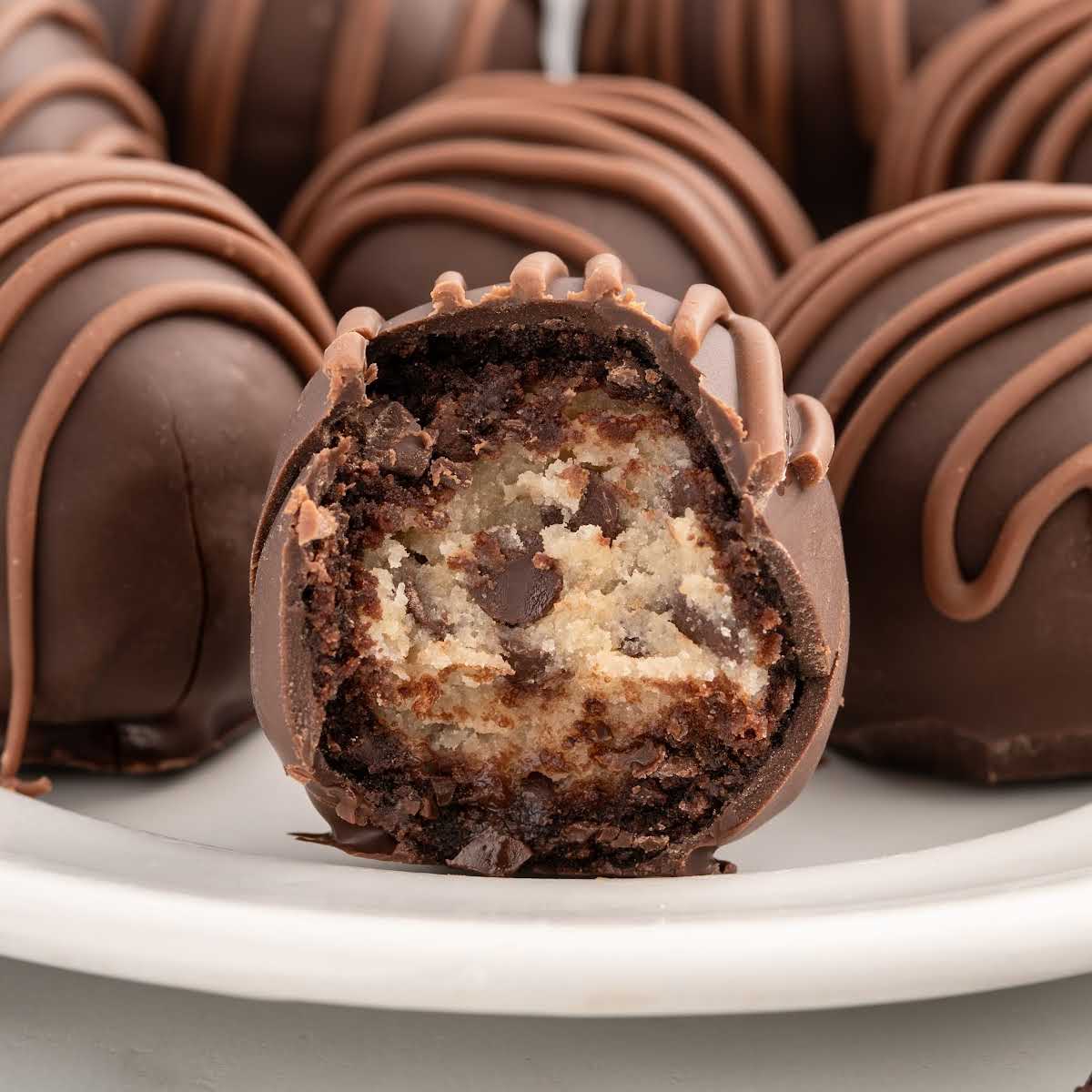 Stylized recipe card image showcasing a plate of chocolate chip cookie dough brownie bombs with a focus on their rich chocolate coating and edible cookie dough centers.