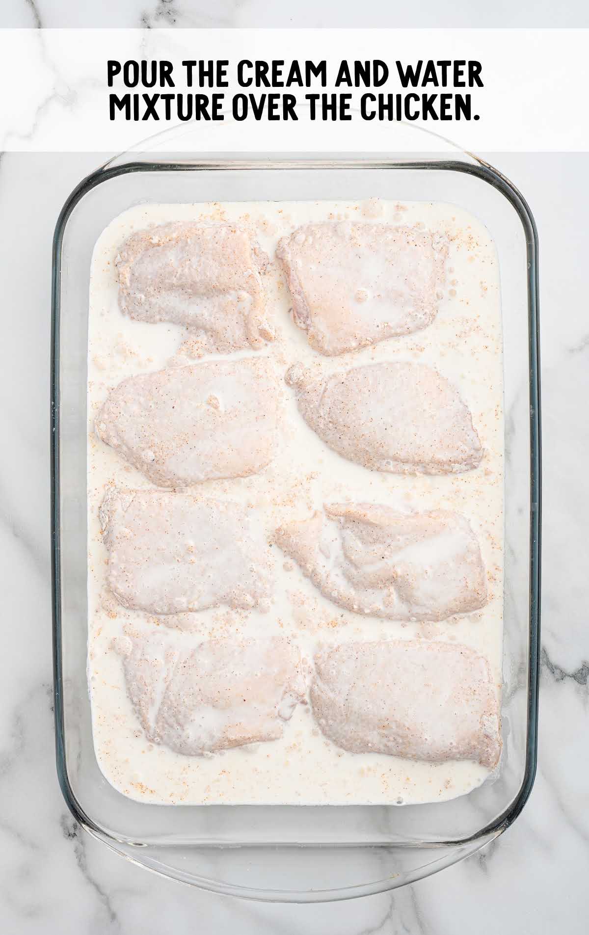 cream and water poured over the chicken in the baking dish