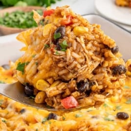 A clean, bright photo of chicken enchilada rice casserole served from the baking dish, with a focus on the textures and ingredients, perfect for a blog post feature.