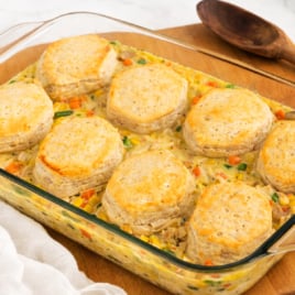 Chicken pot pie casserole with fluffy golden biscuits baked on top of a creamy chicken and vegetable filling in a glass baking dish