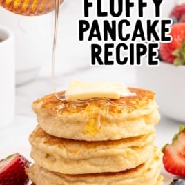 fluffy pancakes stacked on top of each other and topped with a slice of butter and syrup on a plate with fruit