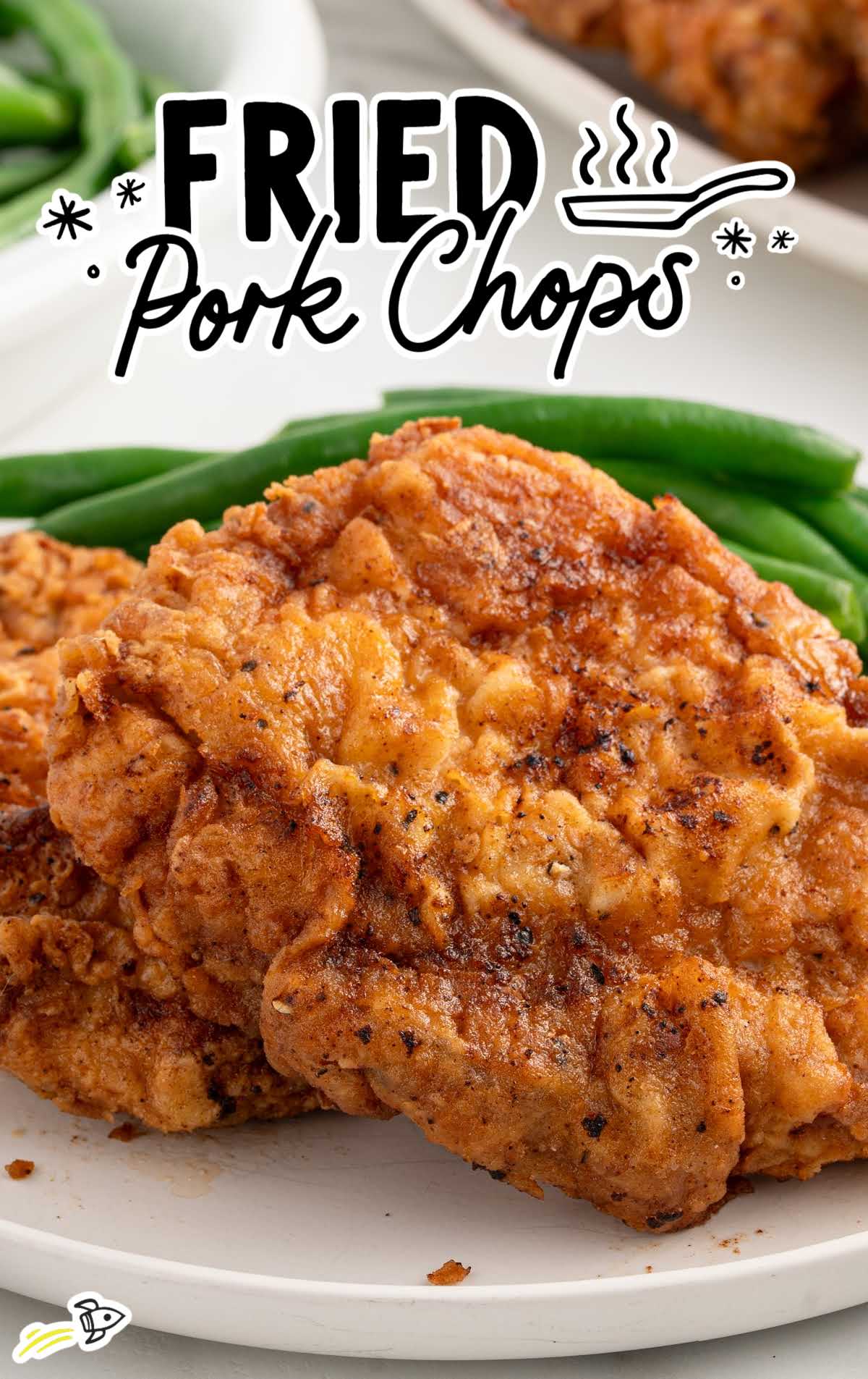 Stack of golden brown fried pork chops served on a plate with green beans.