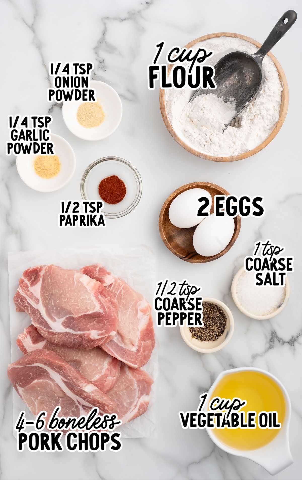 Overhead view of ingredients for fried pork chops including pork, flour, eggs, spices, and oil.
