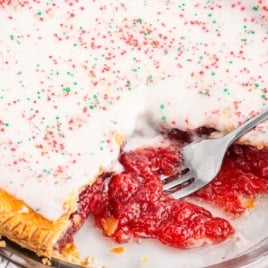 A strawberry pop tart pie in a glass pie plate with a fork scooping out some filling.