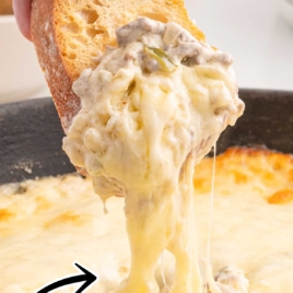 A vibrant close-up of a cheesy Philly cheesesteak dip being scooped with bread, overlaid with bold text reading "Philly Cheesesteak Dip Recipe."