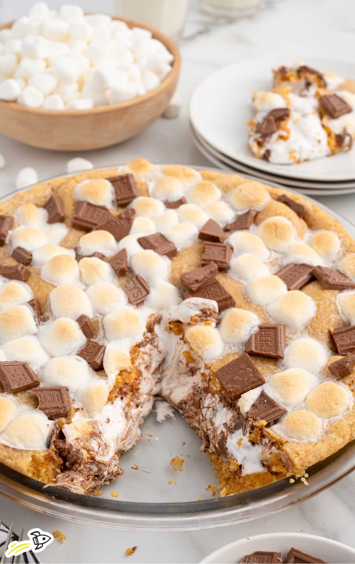 A fork lifting a bite of s'mores pie, showing melted chocolate and marshmallow layers in a golden graham cracker crust.