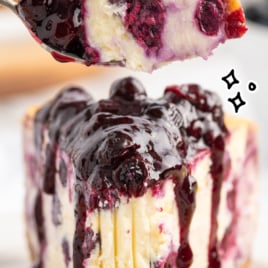 A close up of a piece of Lemon Blueberry Cheesecake with a bit bite taken out of it.