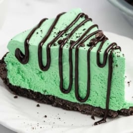 Grasshopper pie in glass pie dish with creamy mint filling and crushed Oreo topping