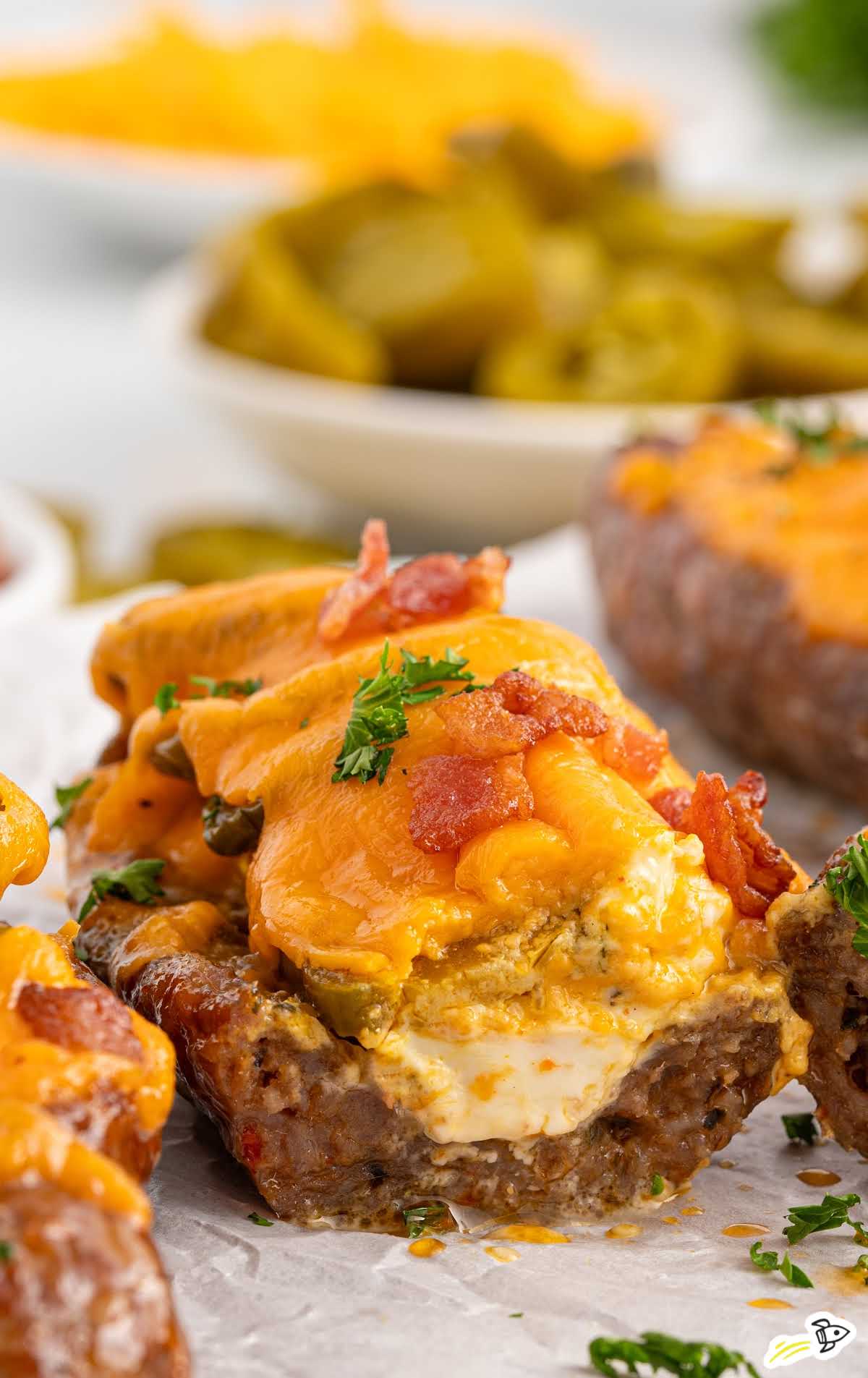 Sliced sausage popper boat showing creamy cheese filling, jalapeños, and melted cheddar topped with bacon.