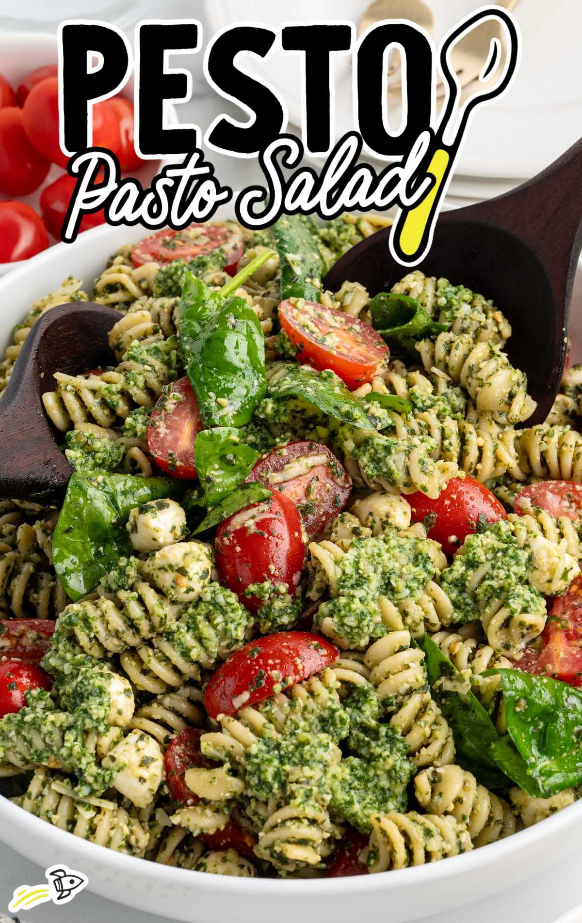 Fresh pesto pasta salad with rotini, spinach, and tomatoes in a white bowl with bold recipe title text overlay.