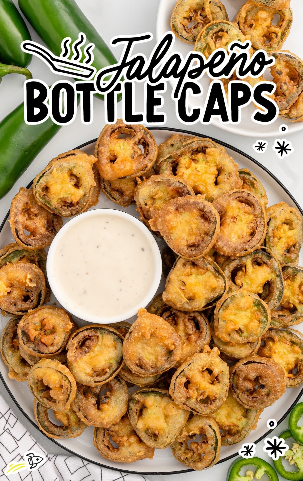 Plate of fried jalapeño bottle caps served with a bowl of ranch dressing and fresh jalapeños on the side