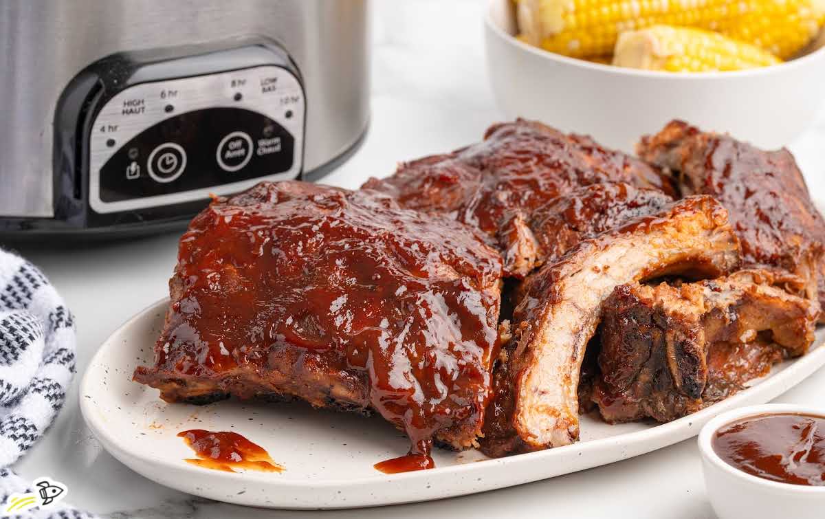 Slow cooker BBQ baby back ribs with tender meat pulling away from the bone and coated in rich barbecue sauce
