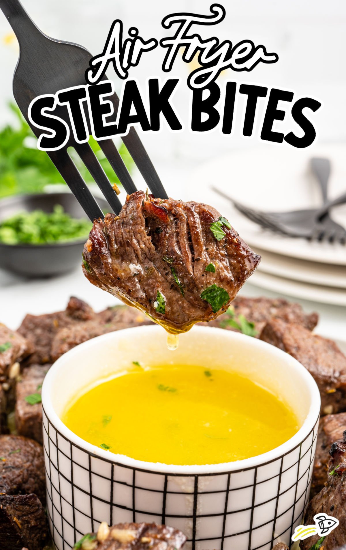 a platter of steak bites with a bowl of melted butter sauce and parsley garnish