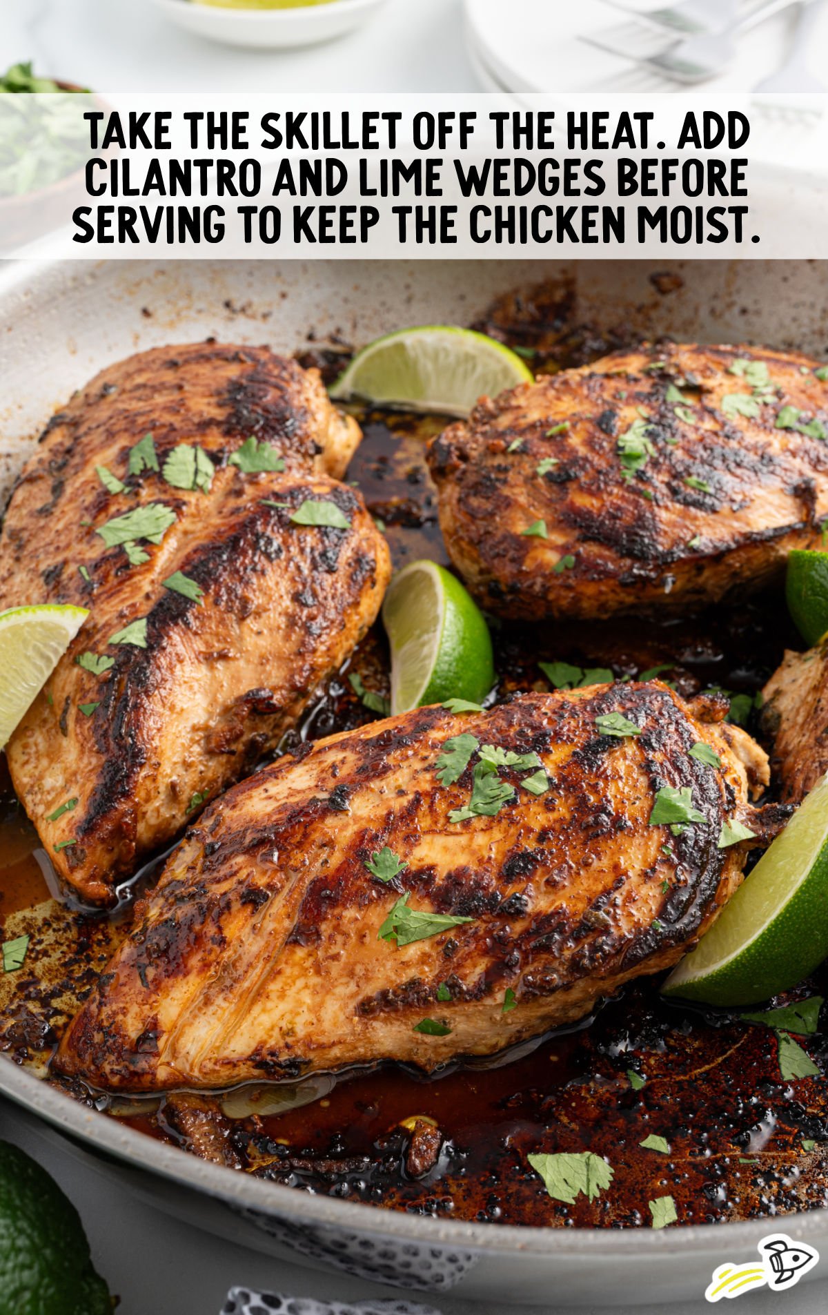 chicken breast garnished with cilantro being cooked on a skillet with slices of lime