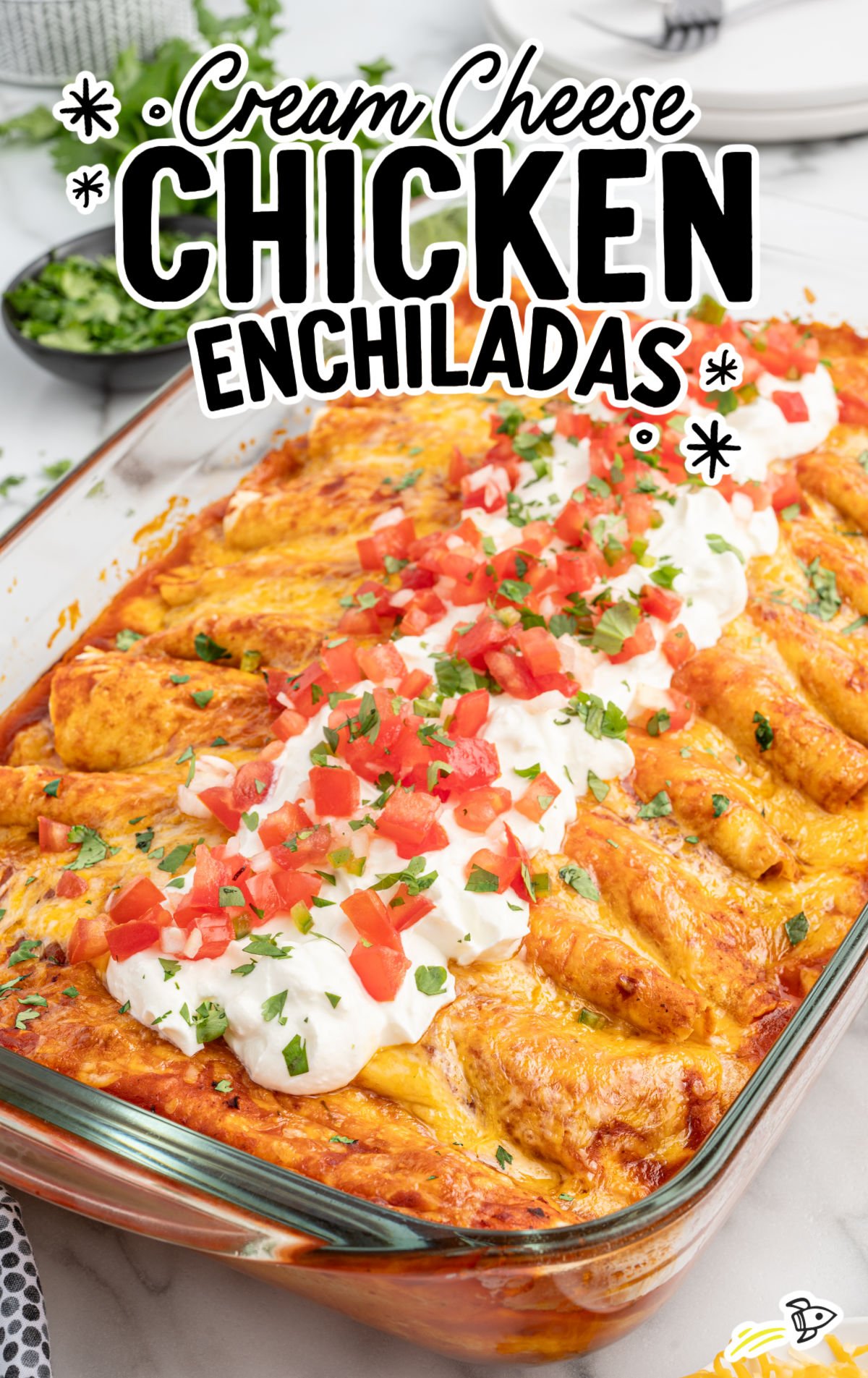 cream cheese chicken enchiladas surrounded by ingredients like shredded cheese, chopped tomatoes, and fresh cilantro, styled for a recipe card.