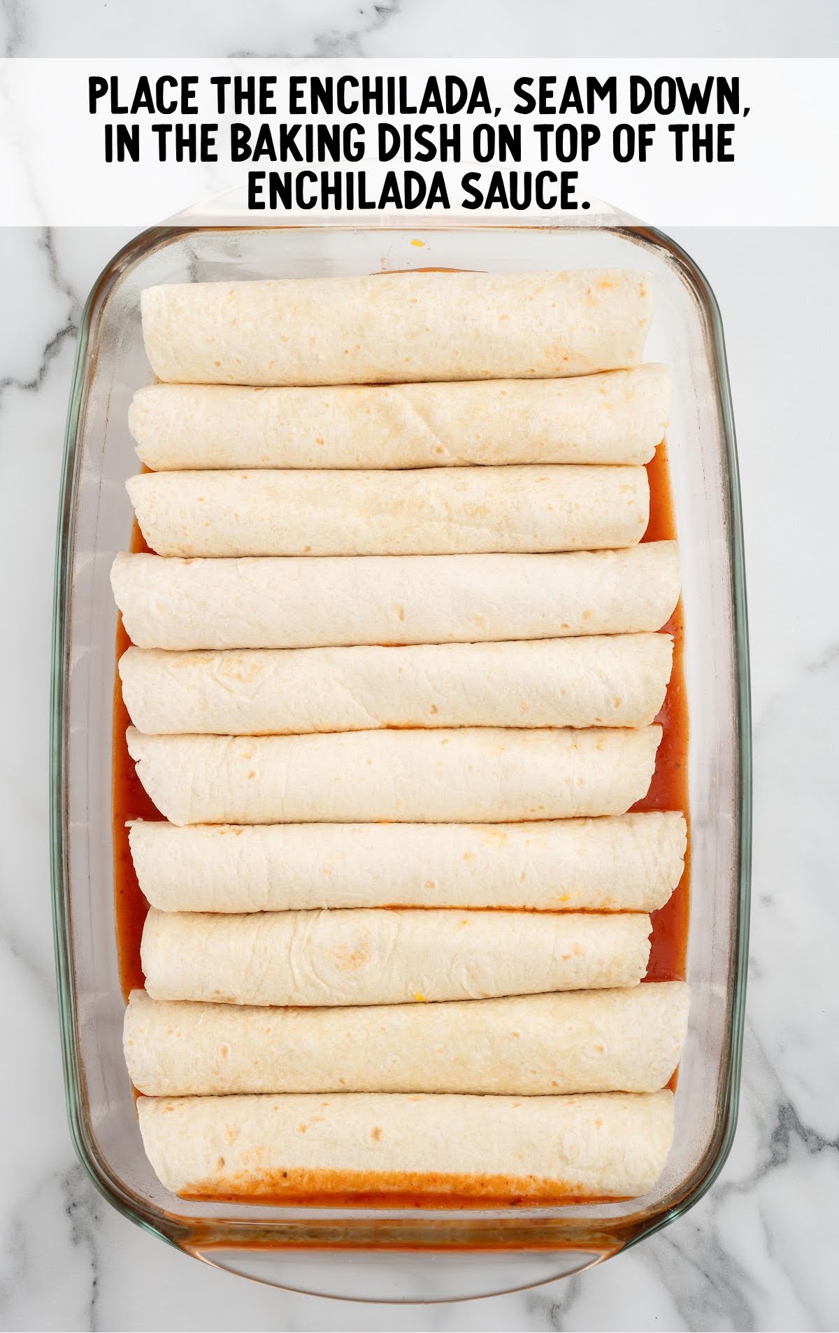 enchiladas placed on top of the enchilada sauce in a baking dish