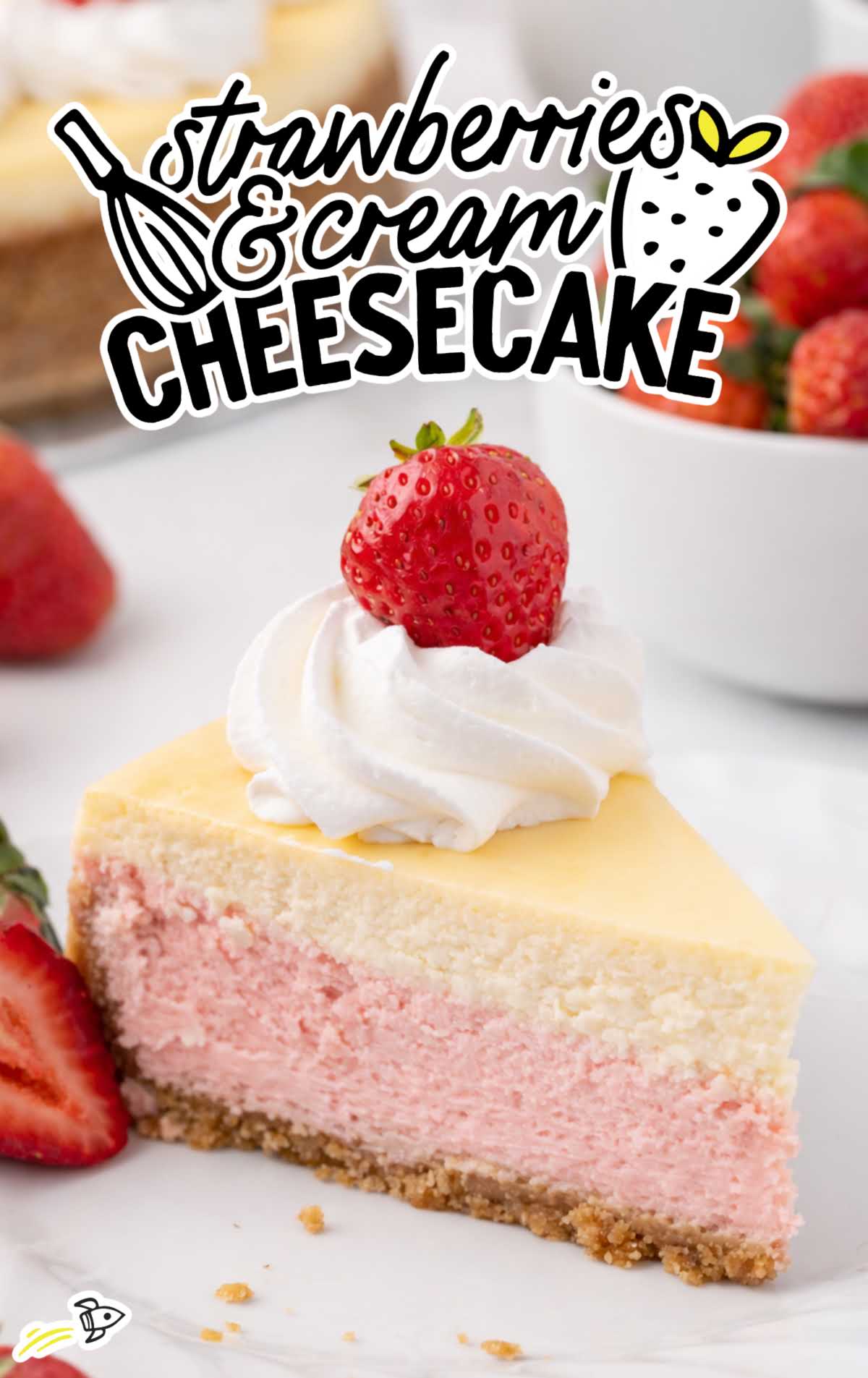 Strawberries and cream cheesecake topped with whipped cream swirls and whole strawberries, one slice removed to show pink and vanilla layers.