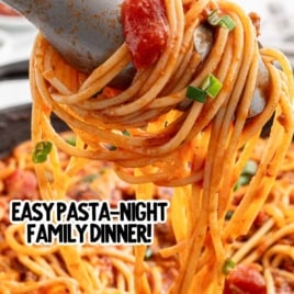 Tongs lifting a serving of cowboy spaghetti from a skillet, with visible chunks of tomato, beef, and green onion, text overlay reads “Ultra Thick & Tasty Cowboy Spaghetti – Easy Pasta-Night Family Dinner!”