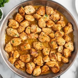 Overhead view of pan filled with browned chicken bites in garlic butter sauce.