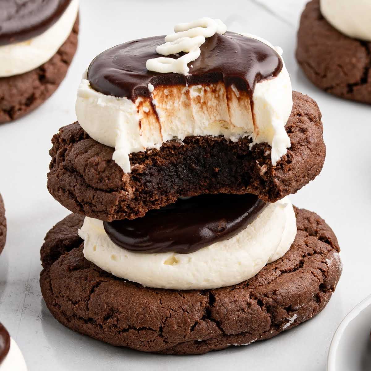 Close-up of a stack of two hostess cupcake cookies with the top cookie bitten to reveal the fudgy center and thick frosting.