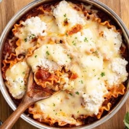 Overhead view of skillet lasagna with bubbly cheese and ricotta dollops in a stainless pan