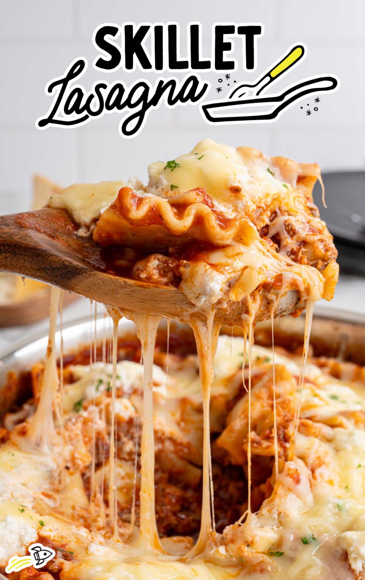 Close view of cheesy skillet lasagna layers lifted on wooden spoon