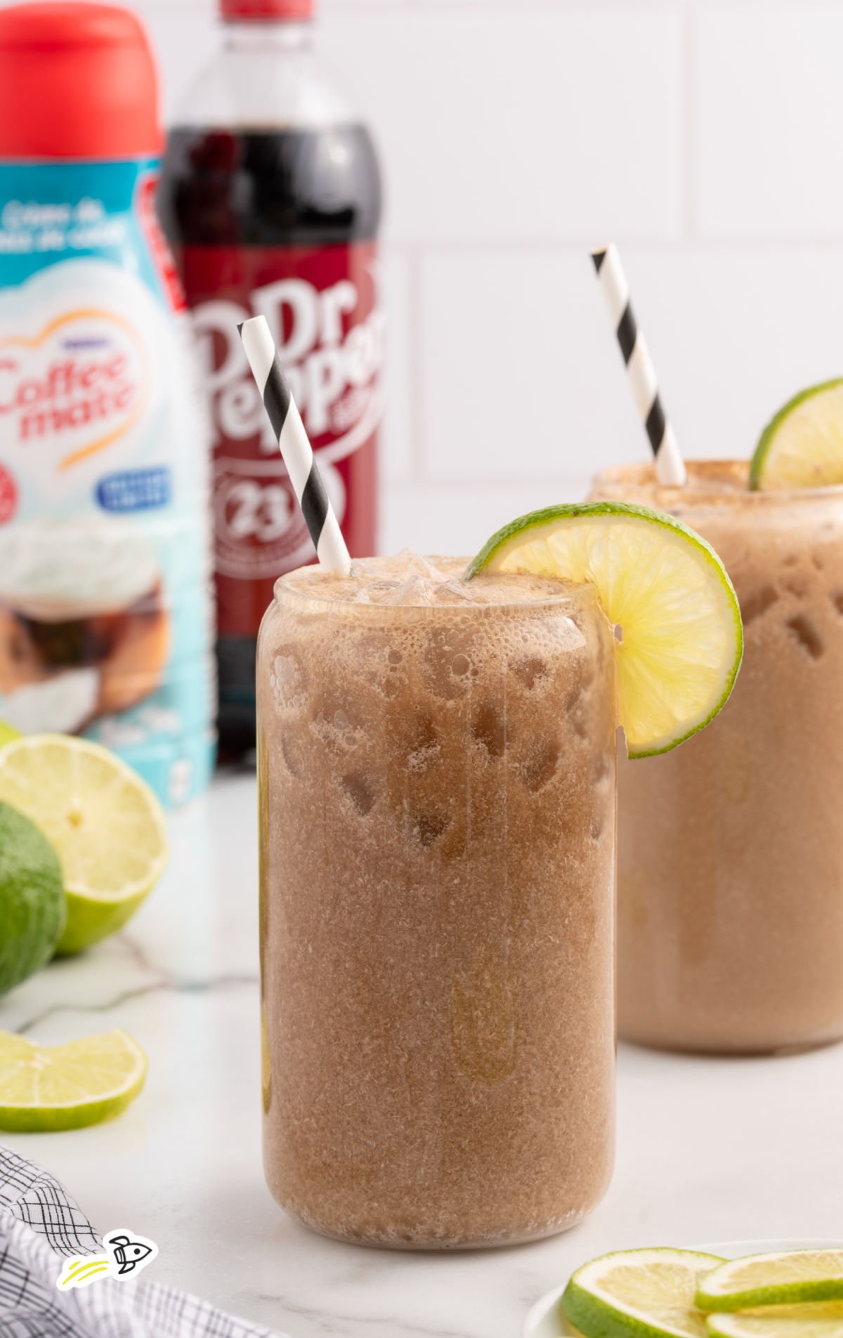 glasses of Dirty Dr Pepper with lime wedges, ice, and straws.