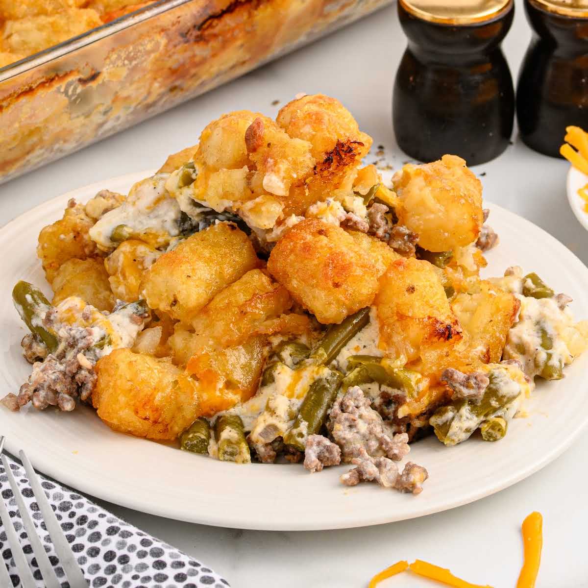 Flat lay of labeled ingredients for hamburger tater tot casserole including tater tots, cheddar cheese, and sour cream.