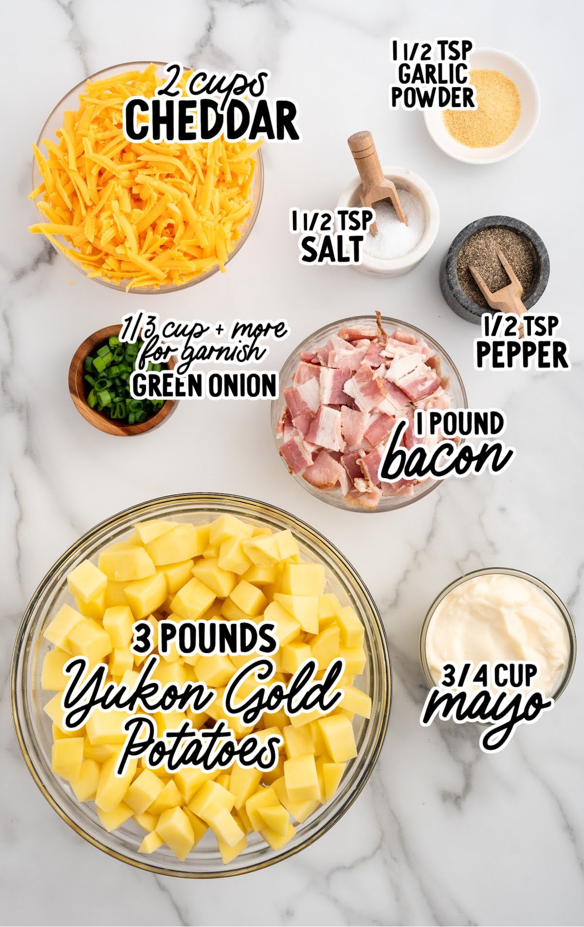 Labeled ingredients for Mississippi Mud Potatoes including Yukon Gold potatoes, cheddar cheese, bacon, green onions, mayo, garlic powder, salt, and pepper.