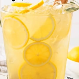 Pitcher of homemade lemonade with sliced lemons and a wood muddler, labeled “How to make perfect state fair lemonade.”
