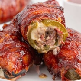 Plate of Texas Twinkies stacked and sliced to reveal the cheesy brisket-stuffed jalapeño center wrapped in crispy bacon.