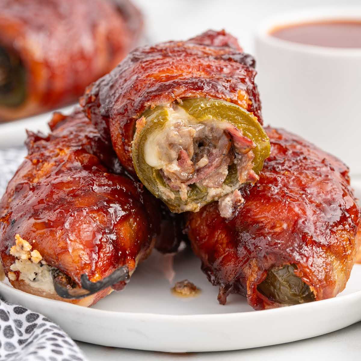 Finished Texas Twinkies served on a white plate with barbecue glaze and a side of dipping sauce.