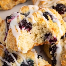 Overhead image of a blueberry biscuit with text overlay: “The Secret to Light & Flaky Blueberry Biscuits – Replicate the Tricks of Your Favorite Bakery!”