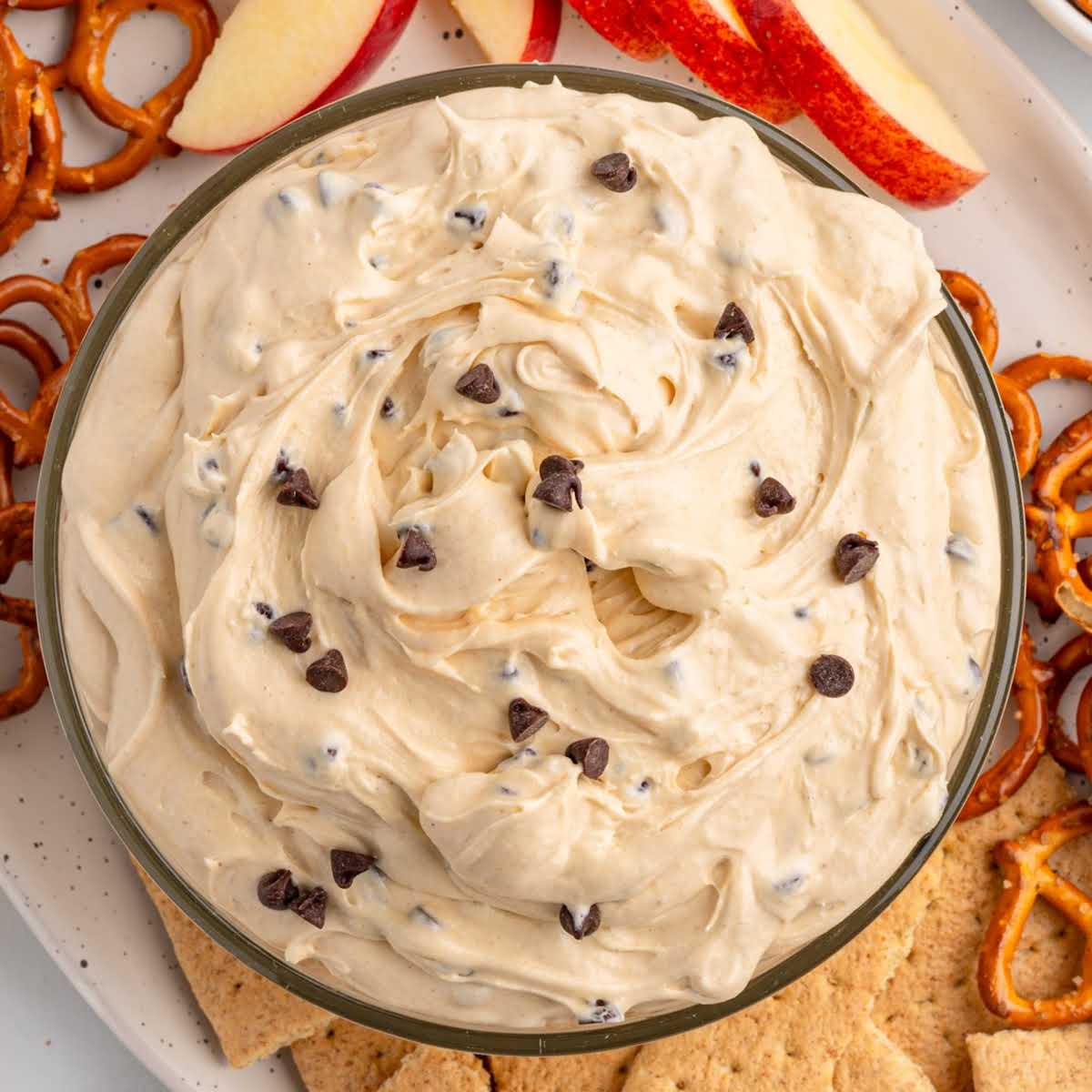 Overhead view of a bowl of buckeye chocolate chip dip surrounded by pretzels, graham crackers, and apple slices.