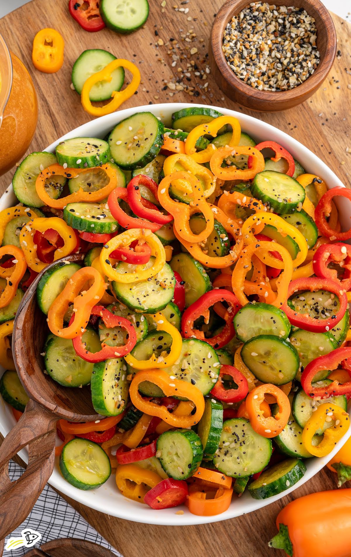 Overhead view of cucumber and bell pepper salad with seasoning and dressing on the side