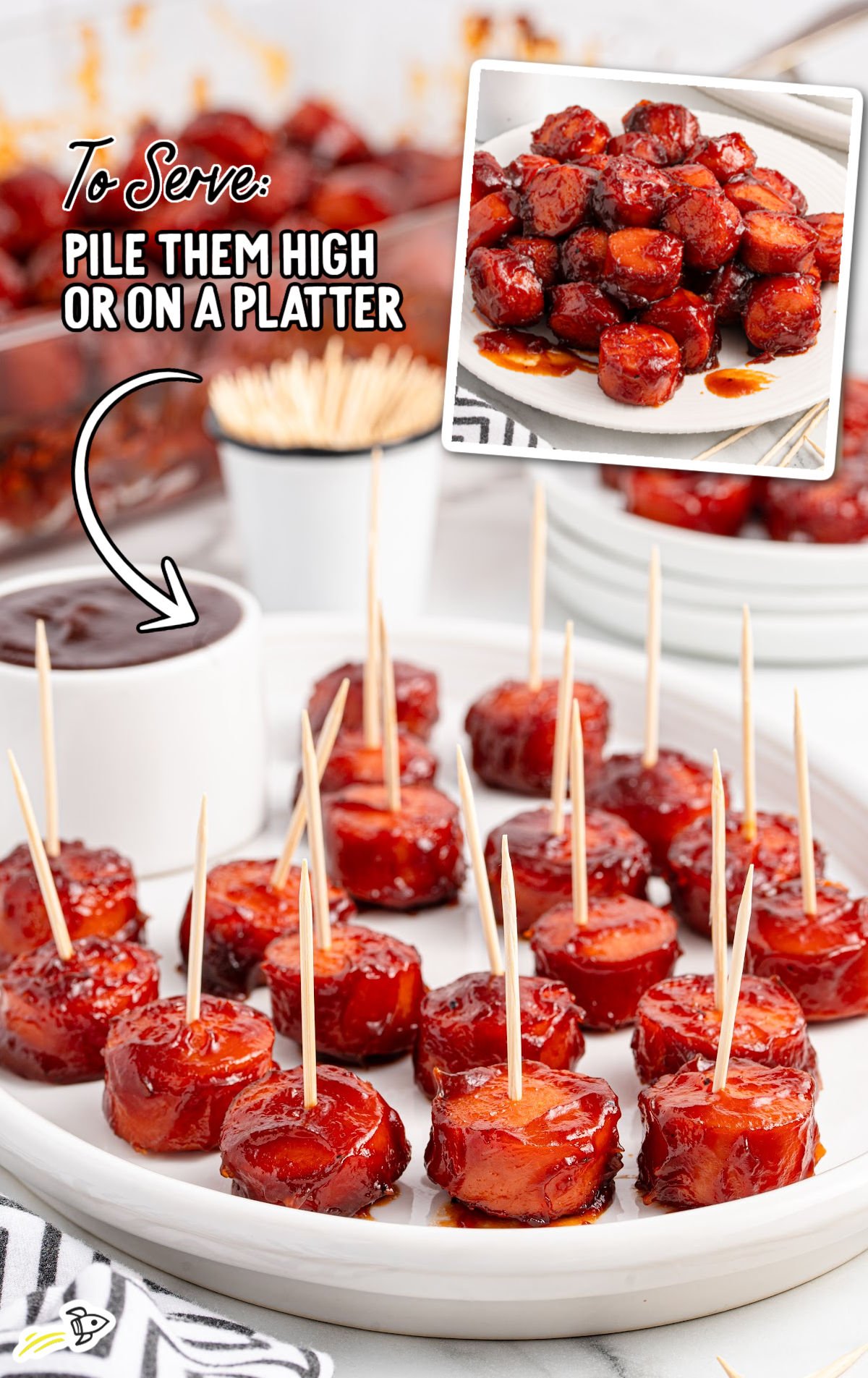 BBQ sausage bites served on a white platter with toothpicks, with a ramekin of dipping sauce and a small bucket of toothpicks in the background. Text overlay offers serving suggestion.