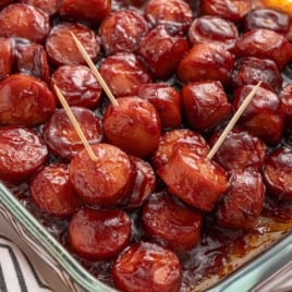 A final close-up of oven-baked BBQ sausage bites in a glass dish, with two pieces on toothpicks for easy serving.