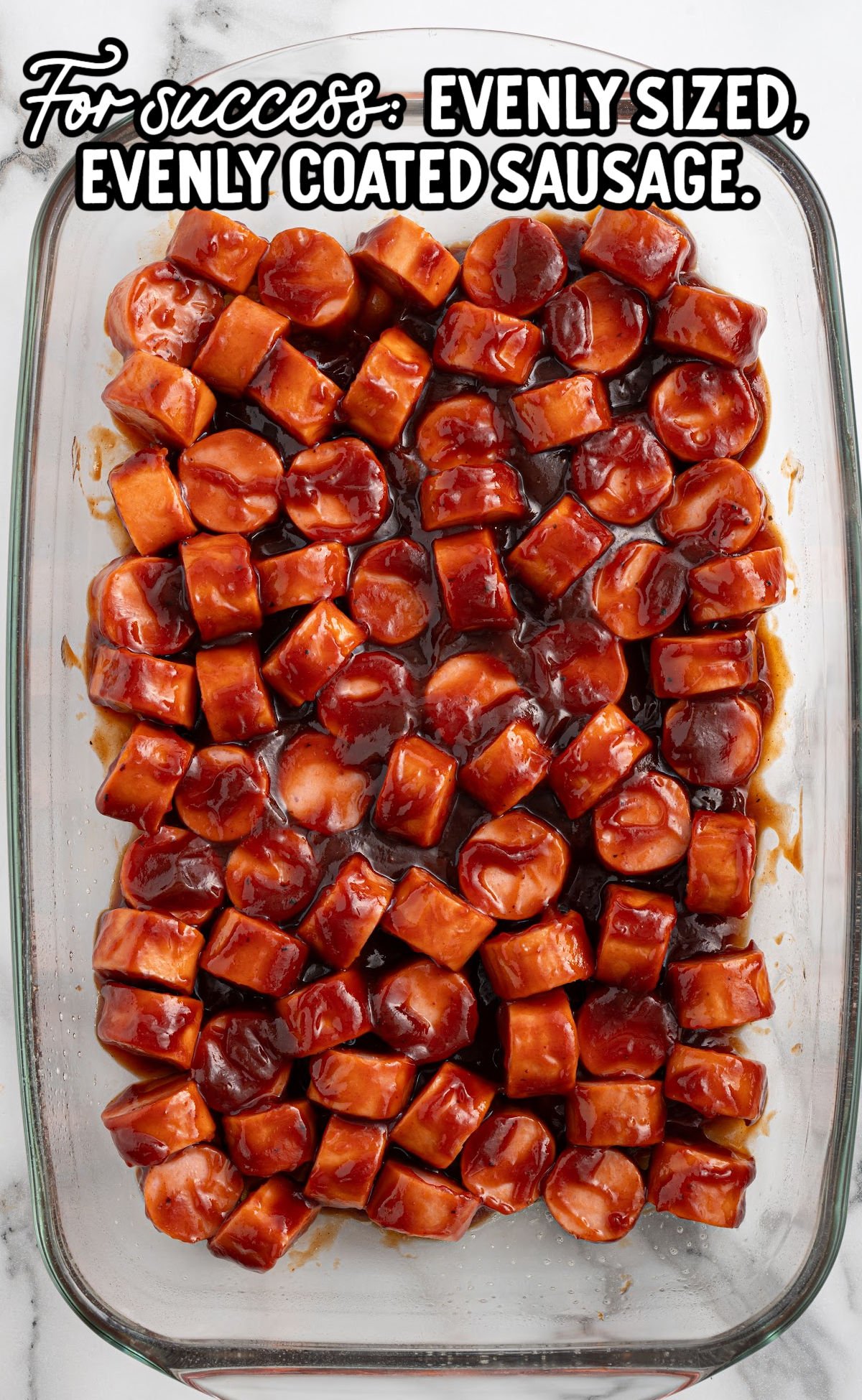 Unbaked sausage slices coated in BBQ sauce, arranged in a single layer in a glass baking dish. Text overlay gives preparation tip for evenly sized, coated sausage.