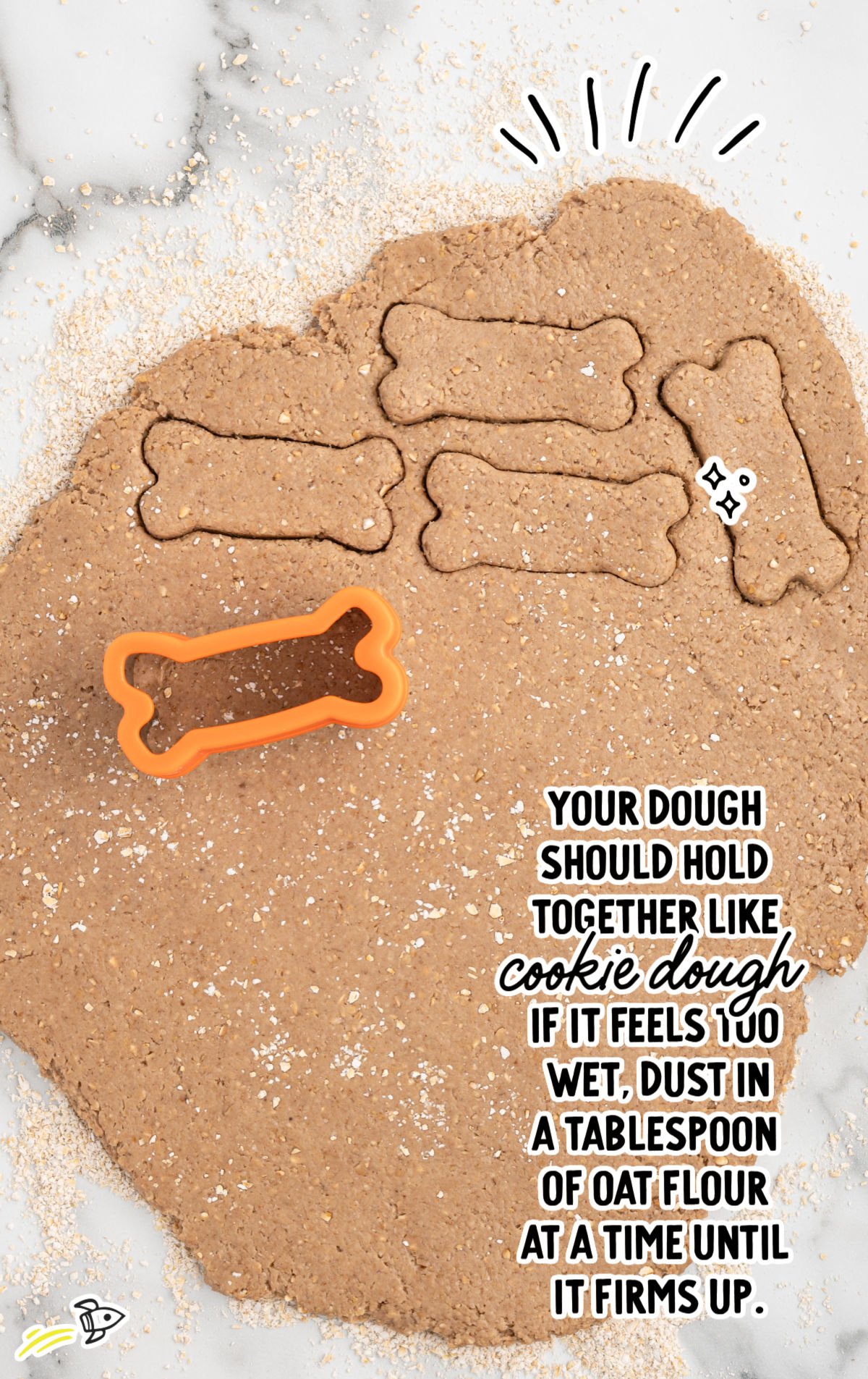 Rolled out dough for banana dog treats with bone-shaped cookie cutter cutting out treats.