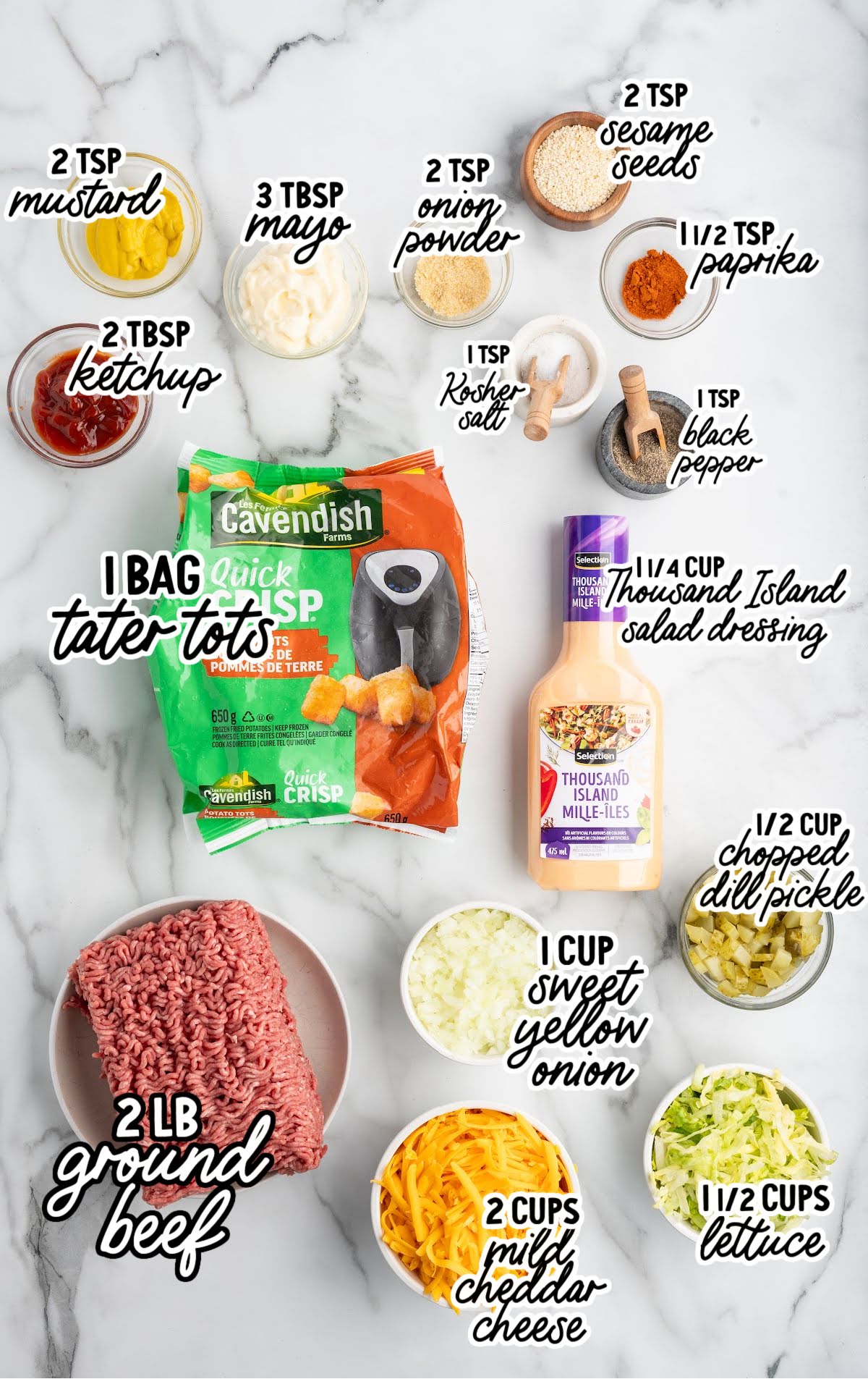 Flat lay of Big Mac tater tot casserole ingredients including ground beef, tater tots, Thousand Island dressing, onion, cheese, lettuce, pickles, and seasonings.