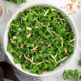 Close-up of a copycat Chick-fil-A kale salad in a white bowl with fresh kale, cabbage, and sliced almonds.