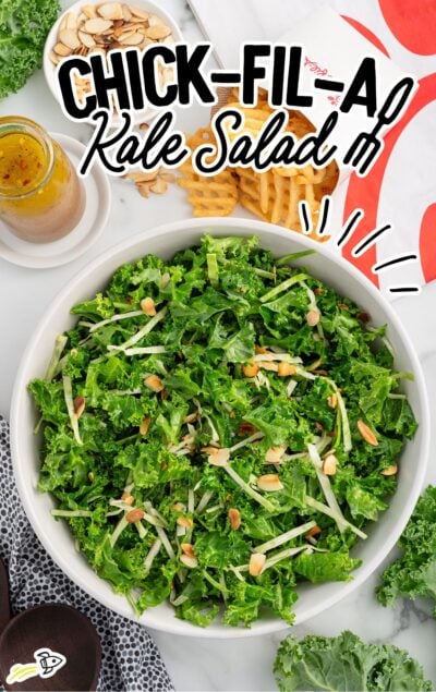 Overhead view of Chick-fil-A kale salad with a small bowl of almonds and dressing beside it on a marble counter.