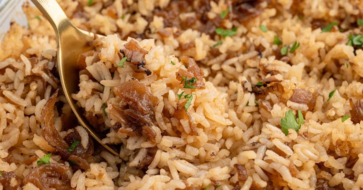 Golden baked French onion rice in a glass dish with caramelized onions and parsley.