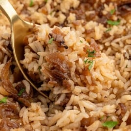 Close-up of French onion baked rice with a gold spoon scooping a serving.
