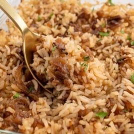 French onion rice topped with caramelized onions and parsley in a casserole dish.