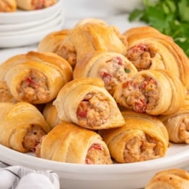 Plate of Rotel sausage and cream cheese crescents stacked on a white dish, perfect for an easy appetizer or party snack.