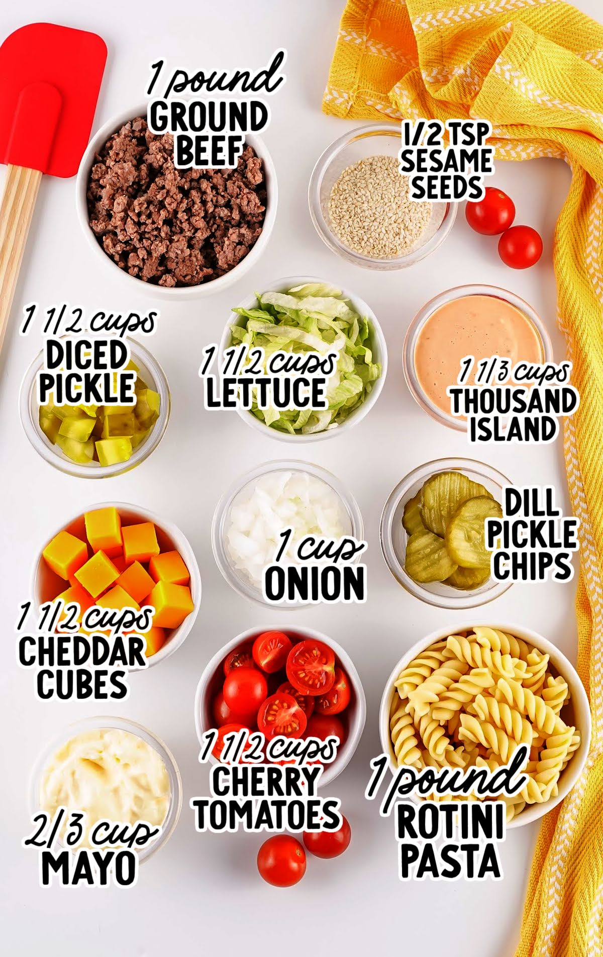Flat lay of Big Mac pasta salad ingredients including ground beef, pasta, cheddar cubes, lettuce, pickles, tomatoes, onion, mayo, and Thousand Island dressing.