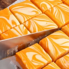 Sliced orange creamsicle fudge squares with bold swirl pattern and smooth glossy finish